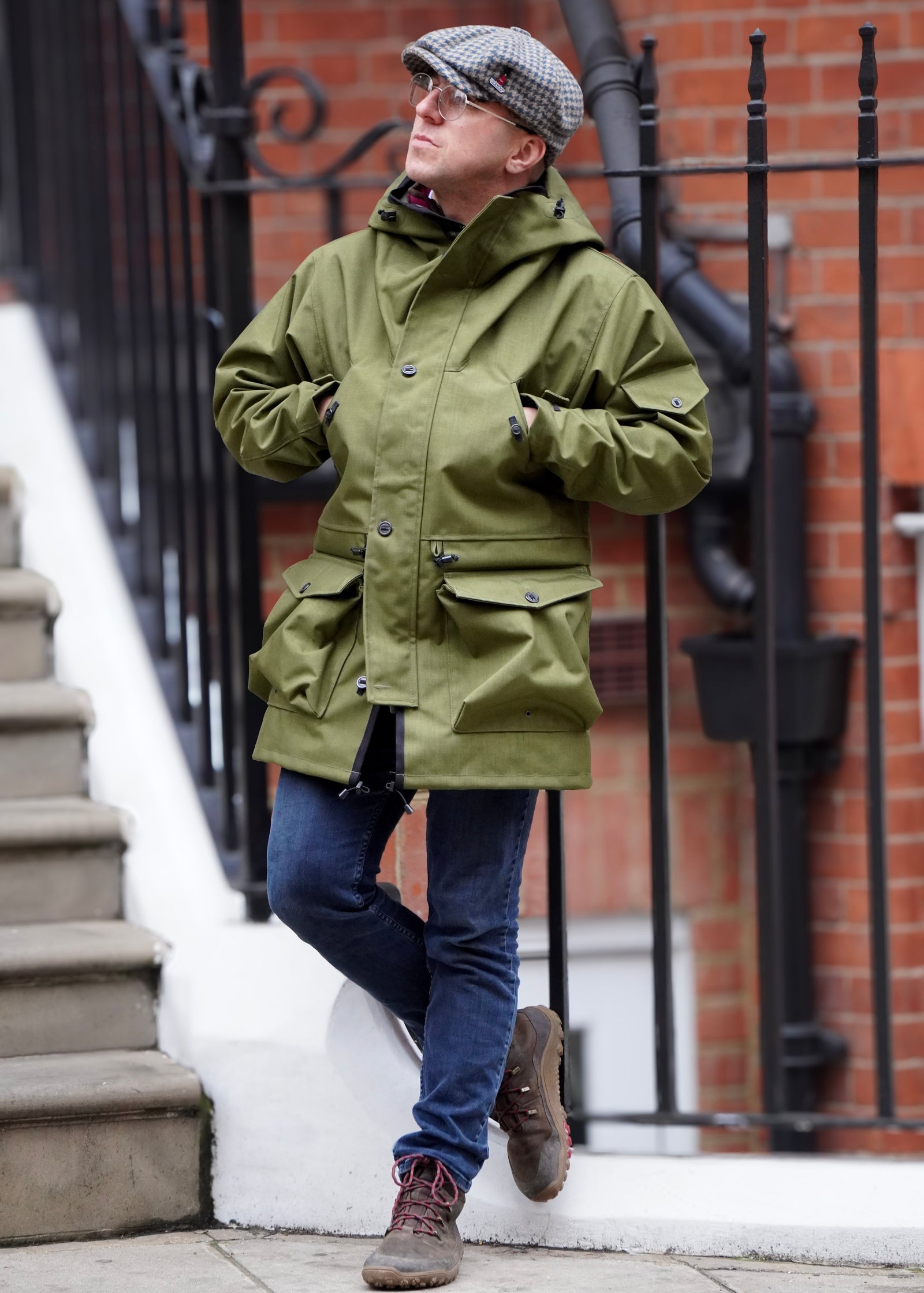 man in urban environment wearing a green waterproof jacket with multiple pockets