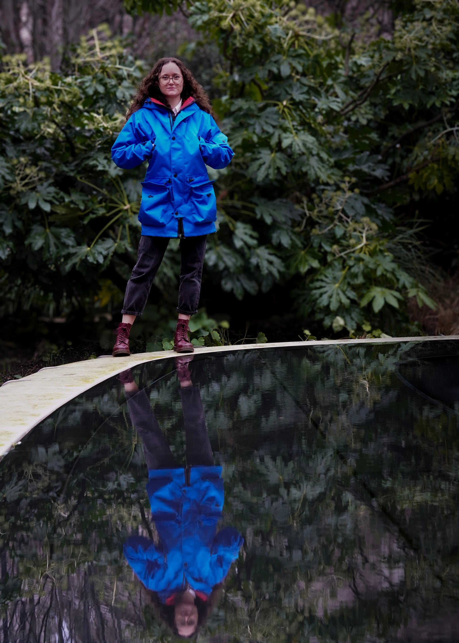 woman standing by a pond in the country wearing a waterproof jacket in royal blue