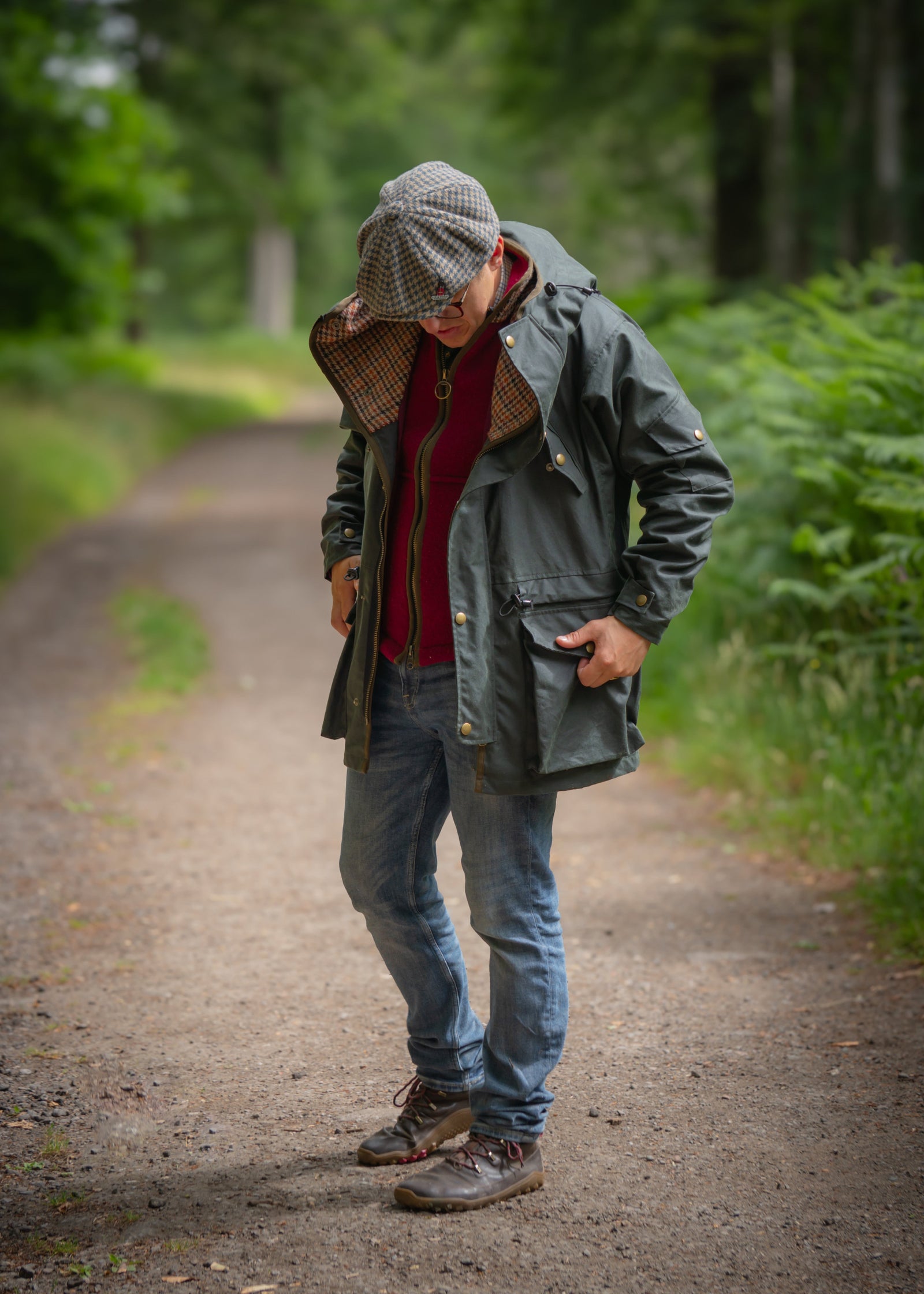 Man wearing a waterproof Lockwood smock jacket in a lush green forest path, showcasing British-made style.