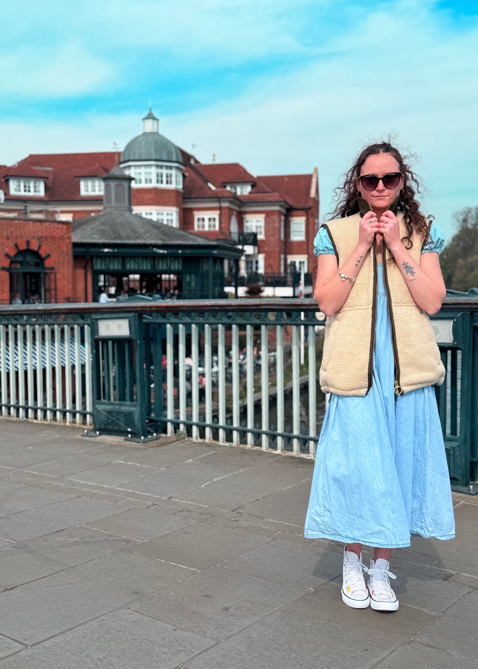 woman standing on a bridge wearing a beige gilet