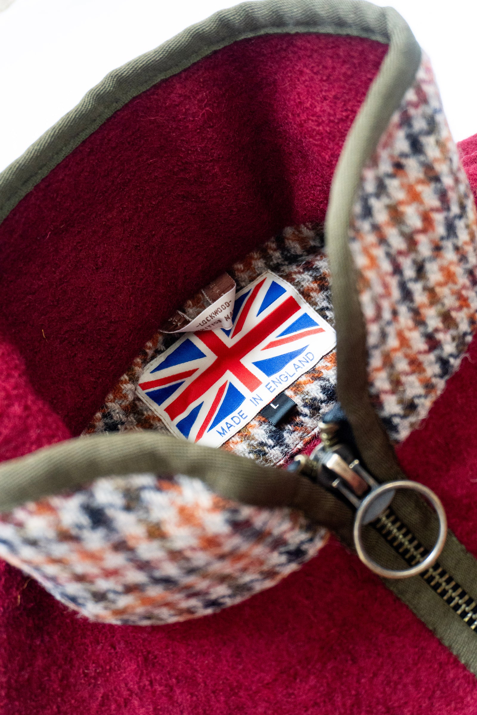 Close-up of a tweed gilet with a Union Jack label and visible zipper.