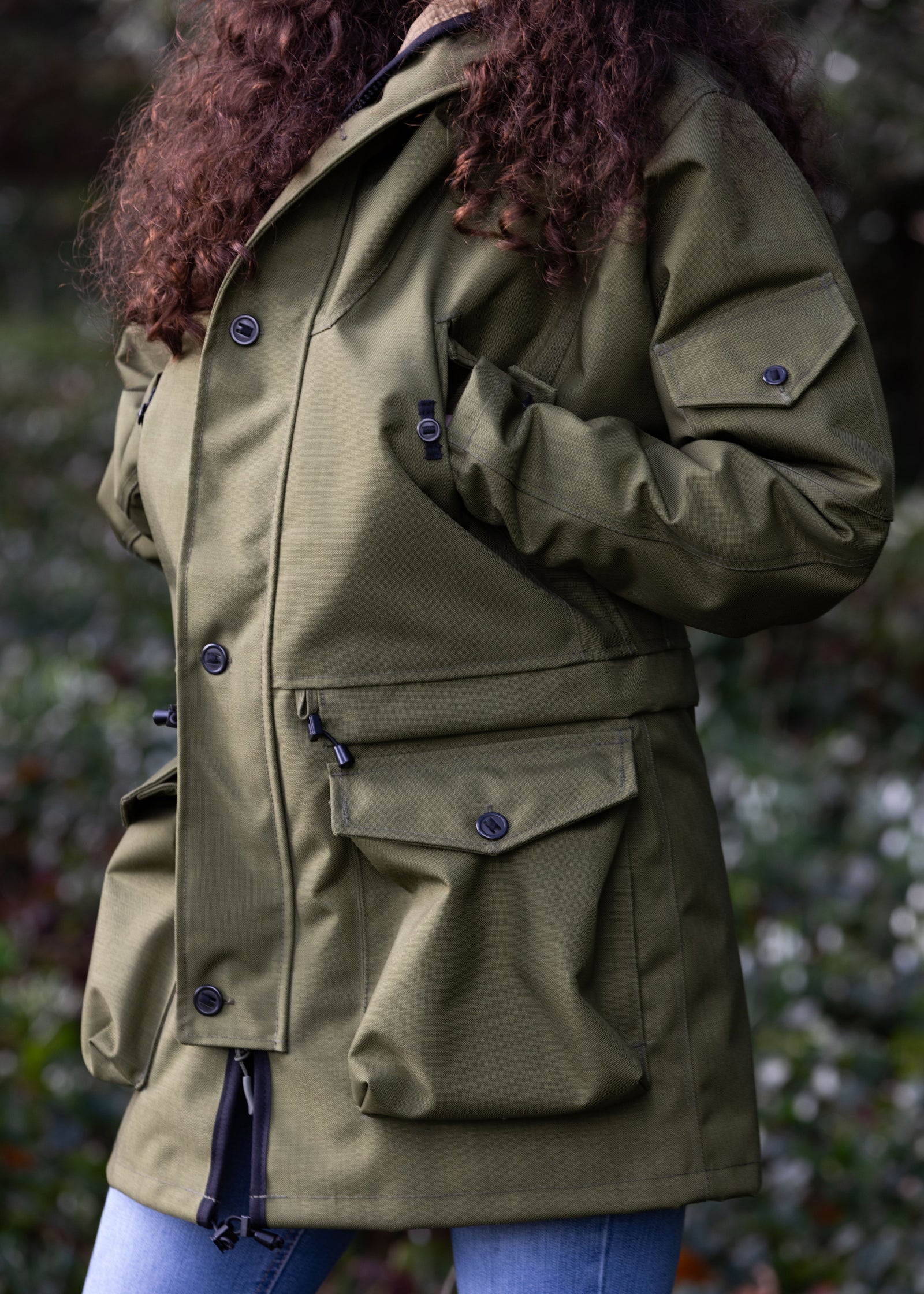 woman wearing a green waterproof jacket with multiple utility pockets