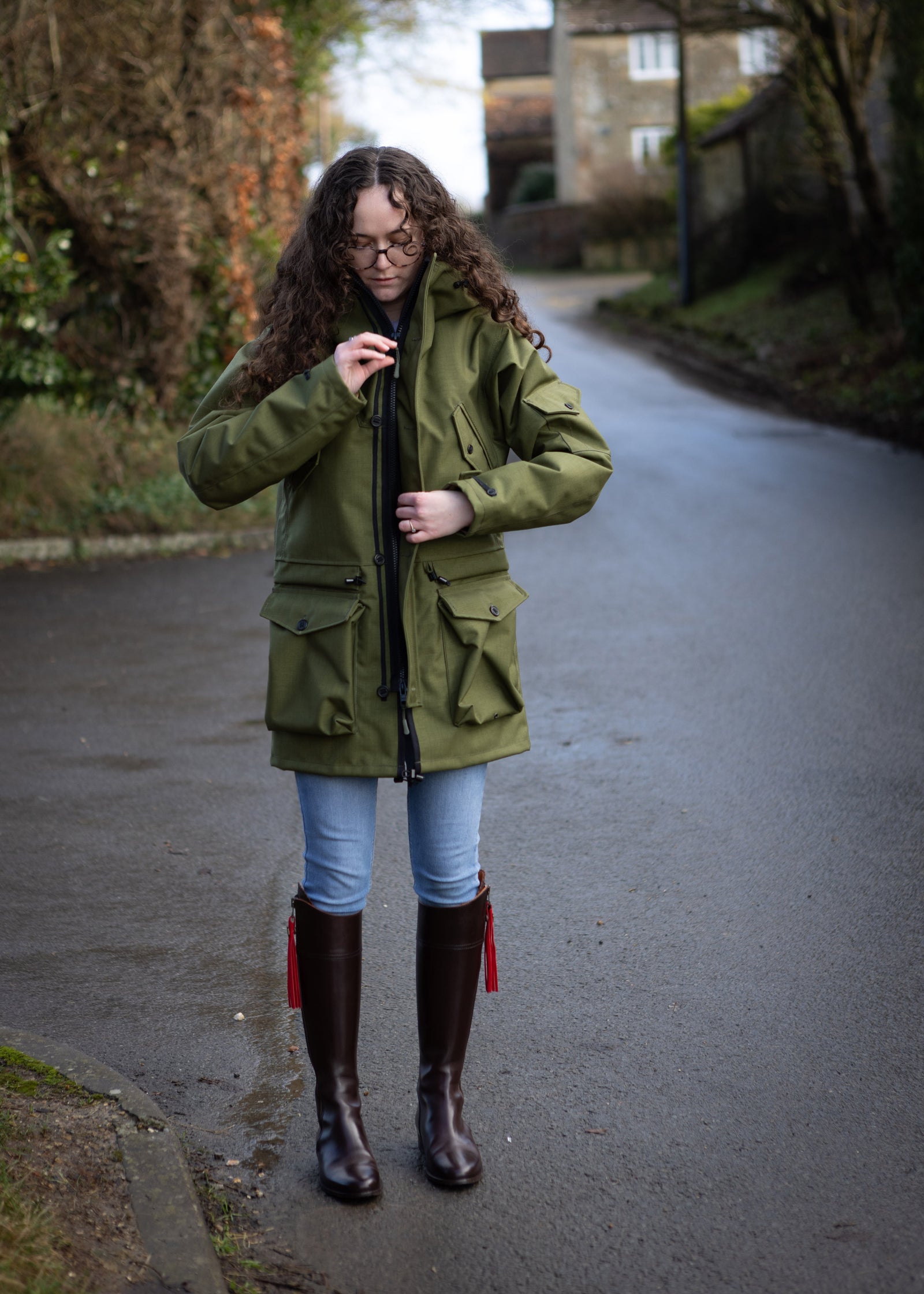 woman zipping up a green waterproof jacket