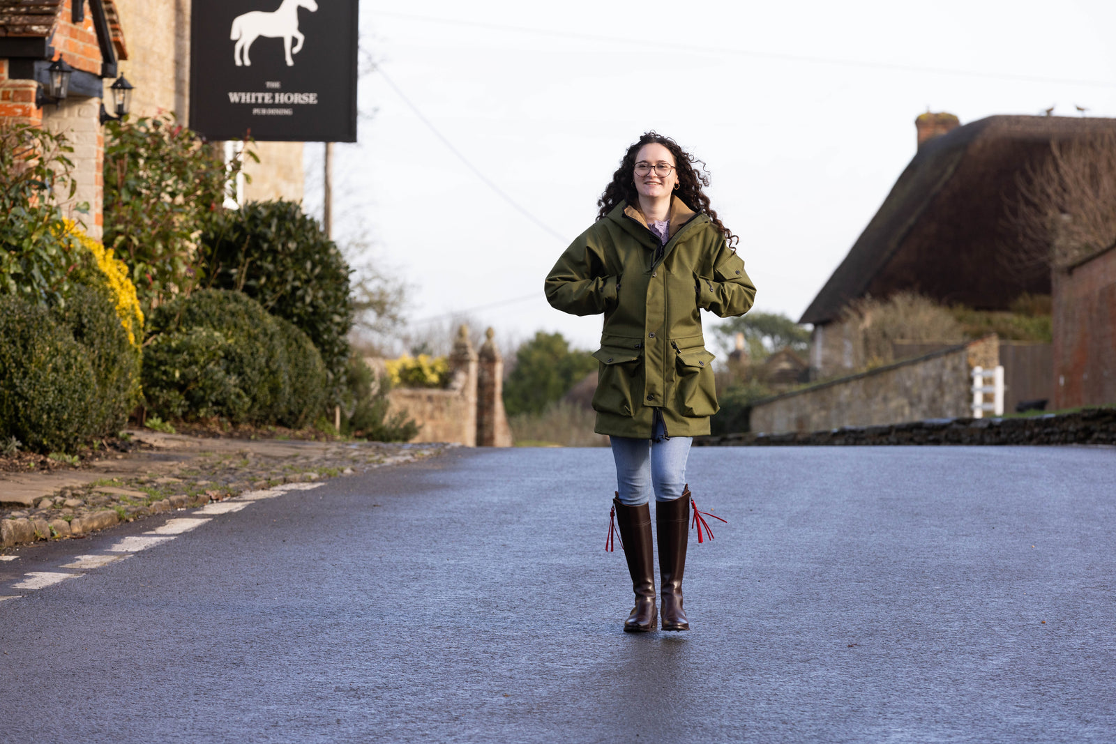 woman walking down a street wearing a green waterproof jacket