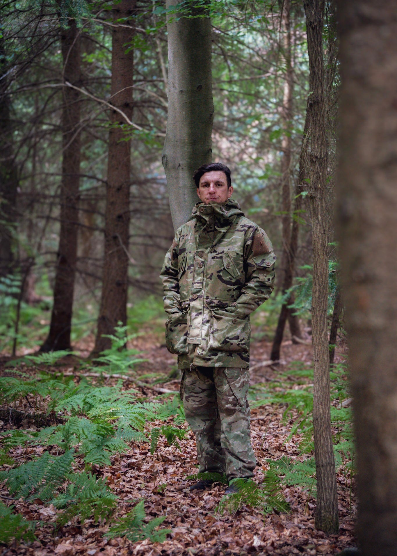 Person wearing camouflage clothing standing in a forest