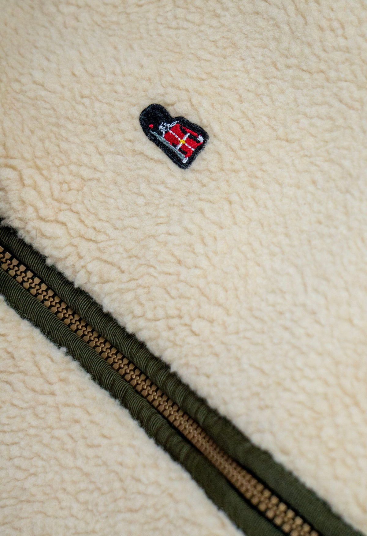 Close-up of a textured fabric surface with a zipper and a small logo.