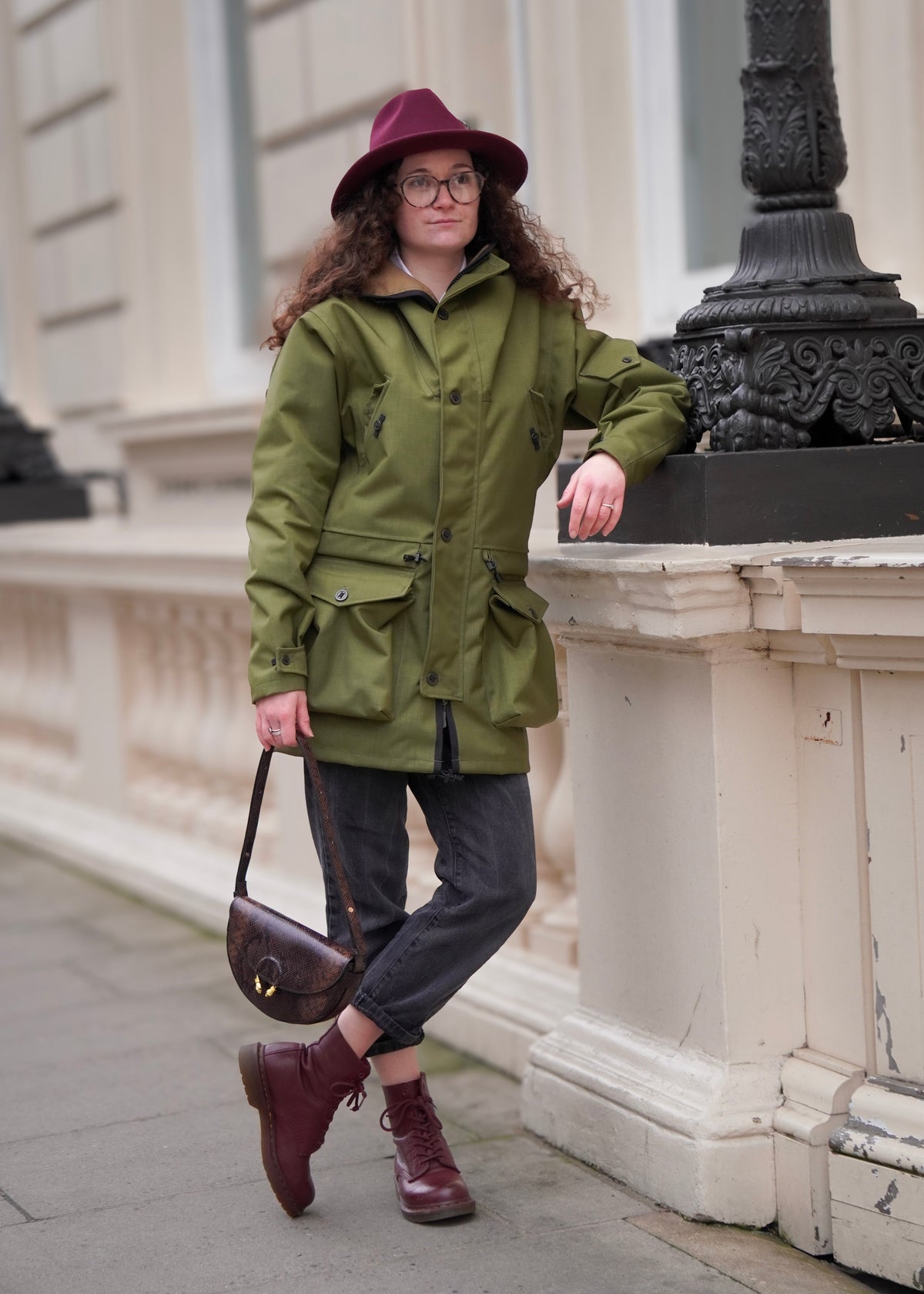 woman in city centre wearing a green waterproof jacket with the hood rolled 