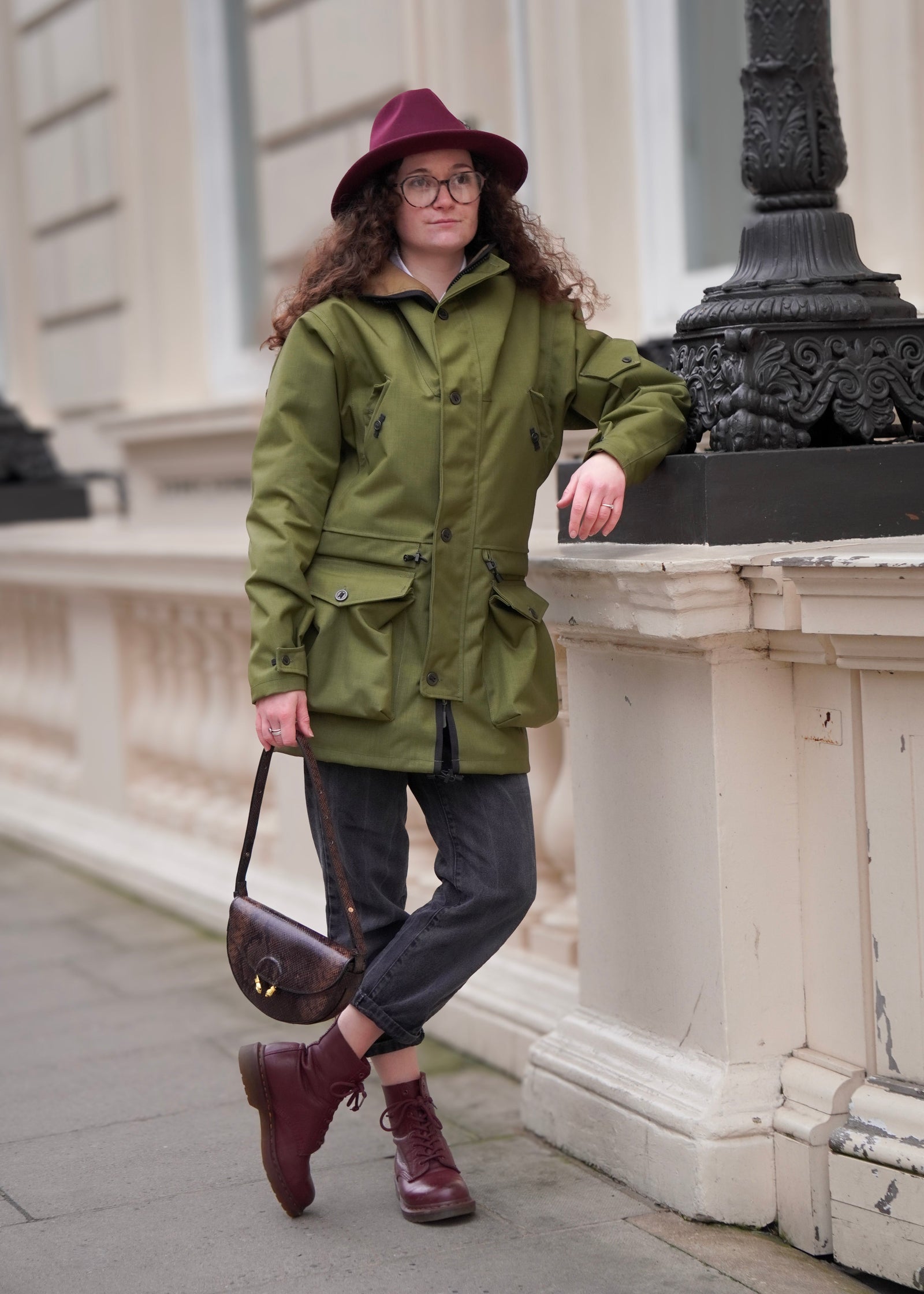 woman in city centre wearing a green waterproof jacket with the hood rolled 