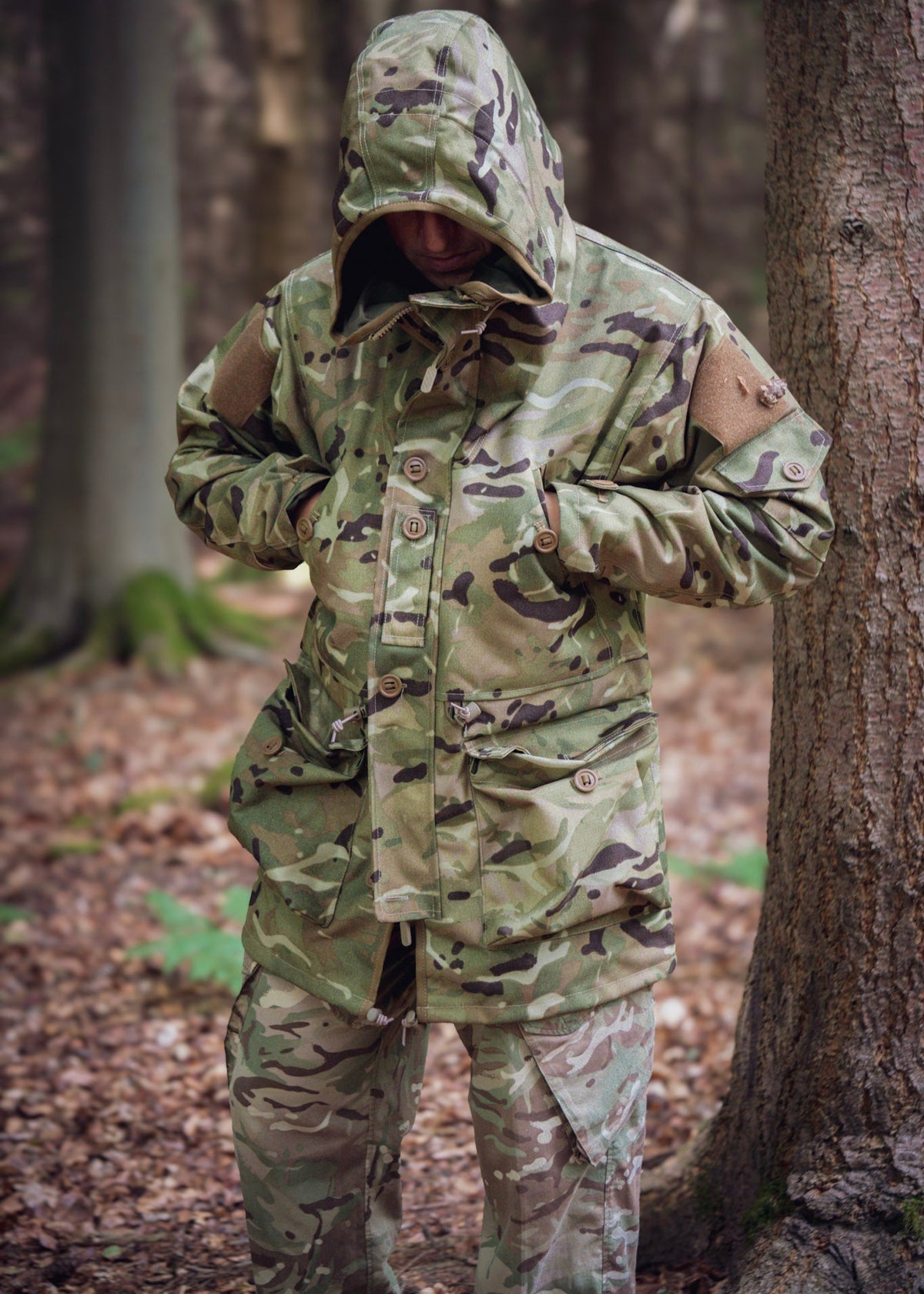 Person wearing a camouflage raincoat and pants in a forest setting