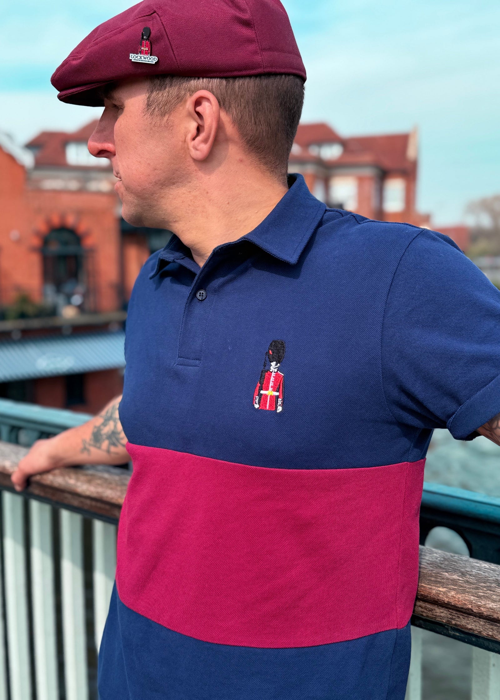 A person wearing a polo top with a red and blue color scheme, featuring a small emblem on the front. The cap wearer is also dressed in a two-tone shirt with a similar color scheme.