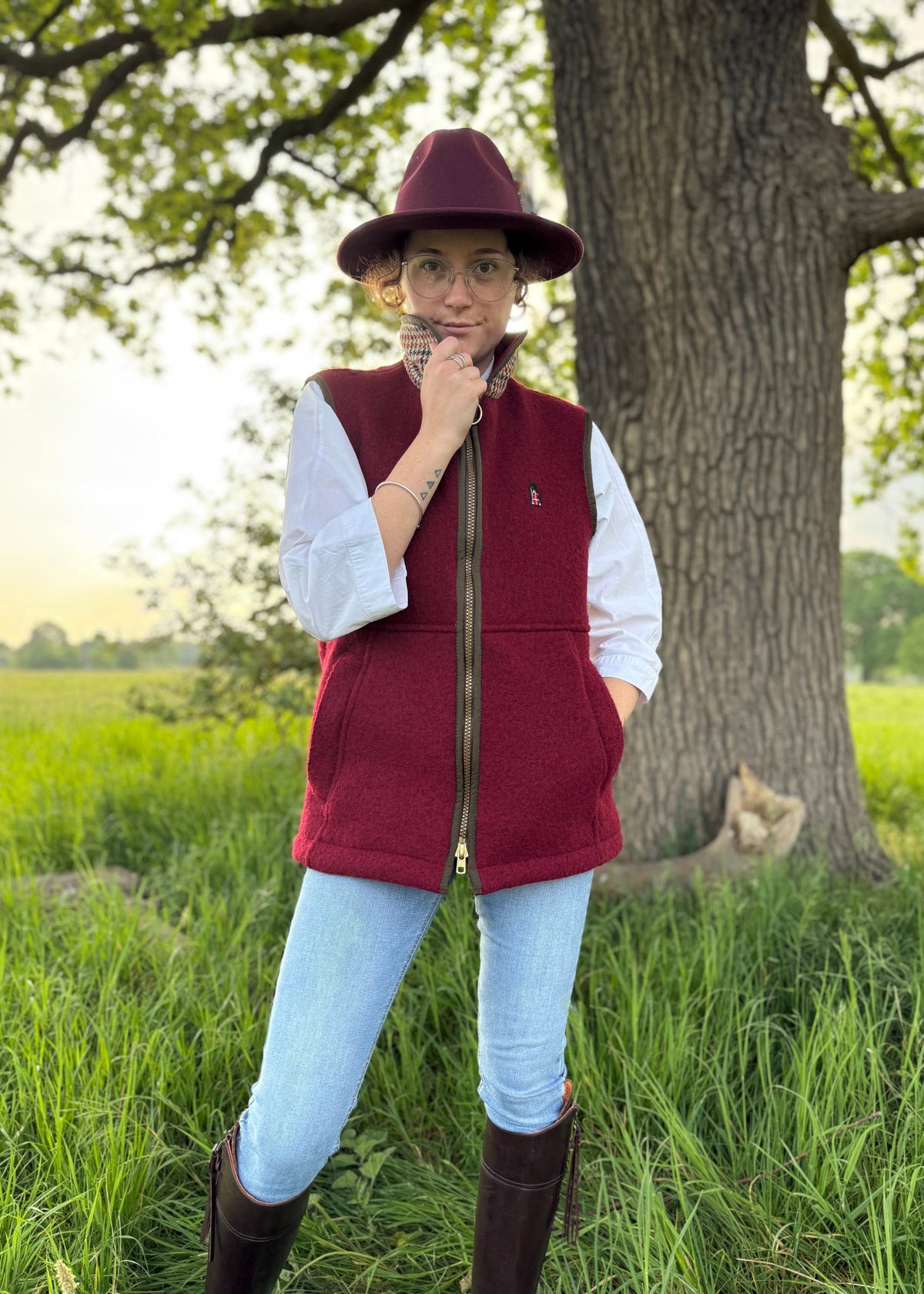 Person in red vest and hat standing in a field