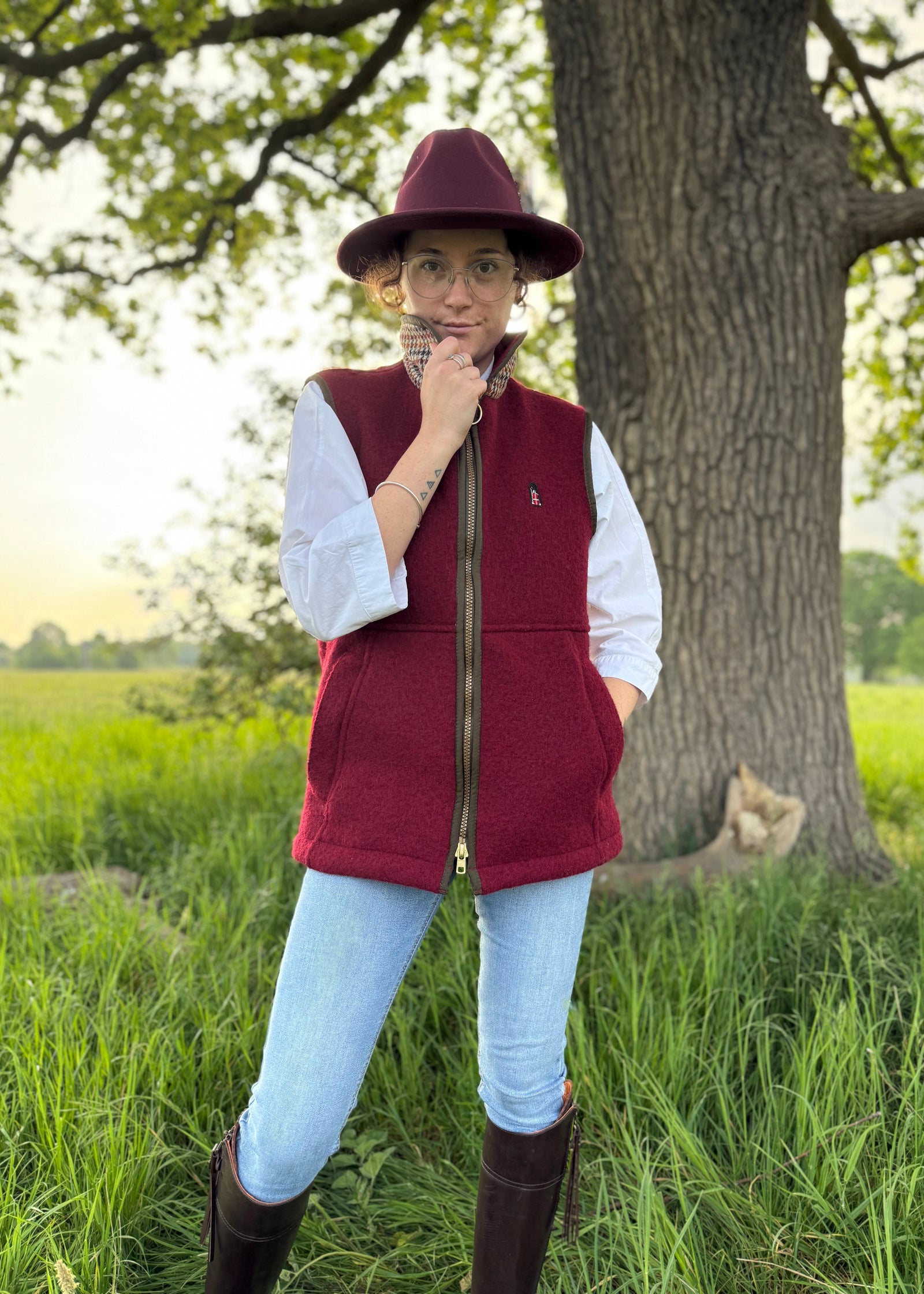 Person in red vest and hat standing in a field