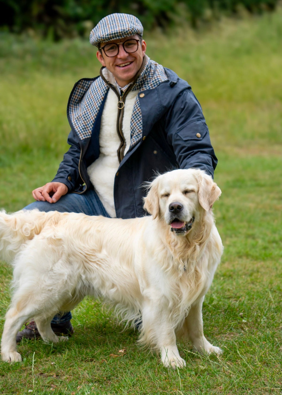 Man sitting on grass with a white dog