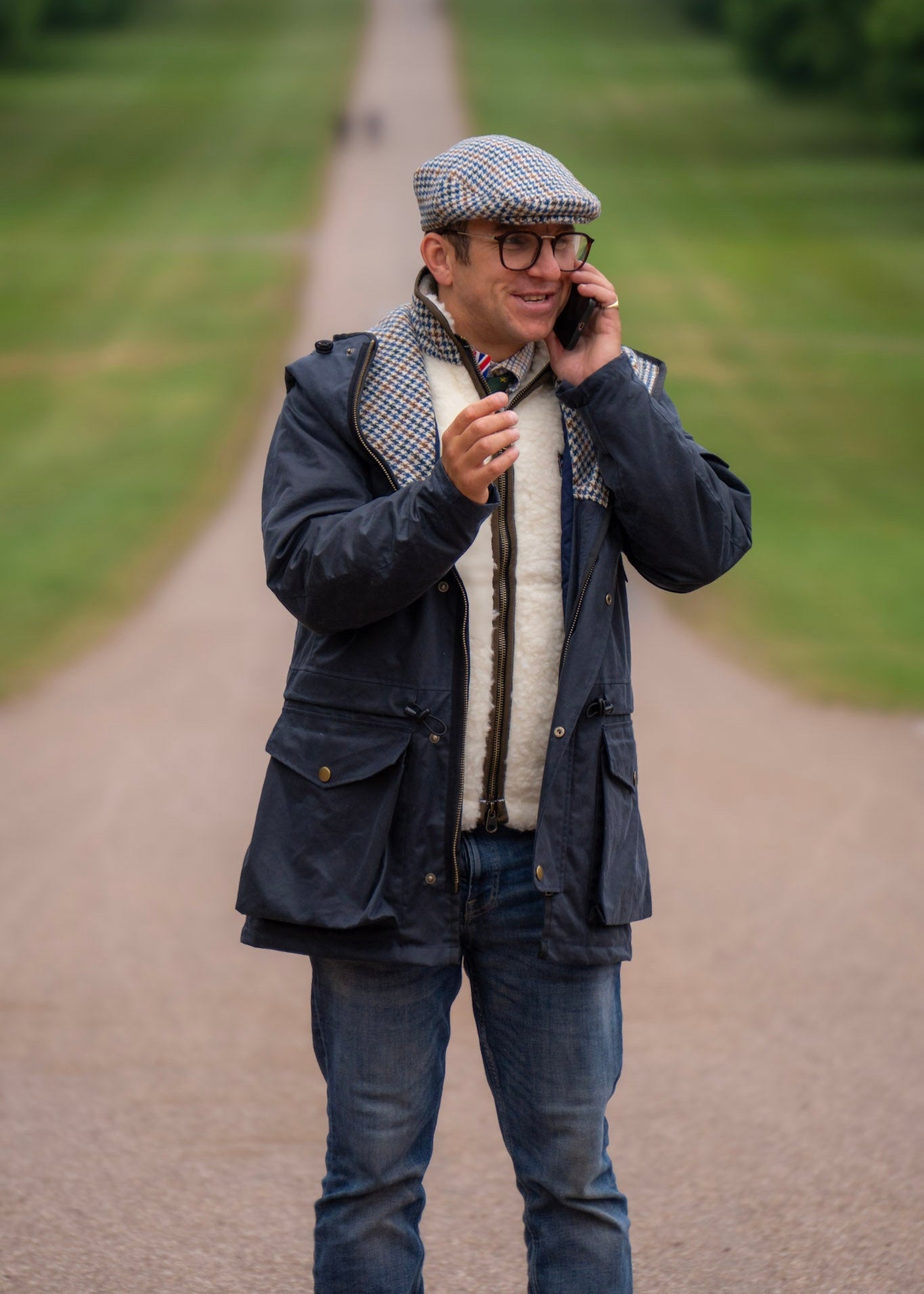 Man talking on a phone in a park wearing a wax jacket