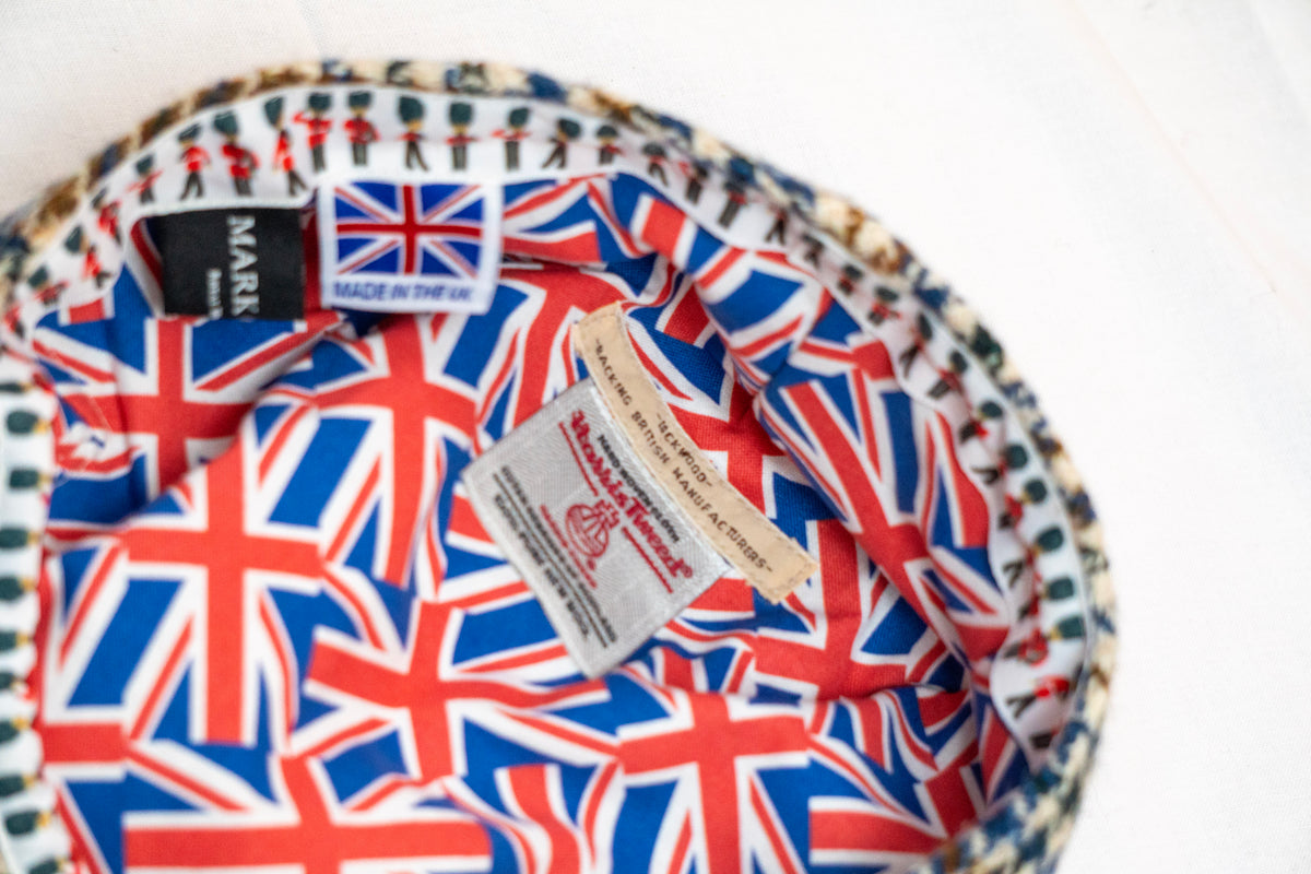 flat cap with Union Jack pattern and brand labels on a white background