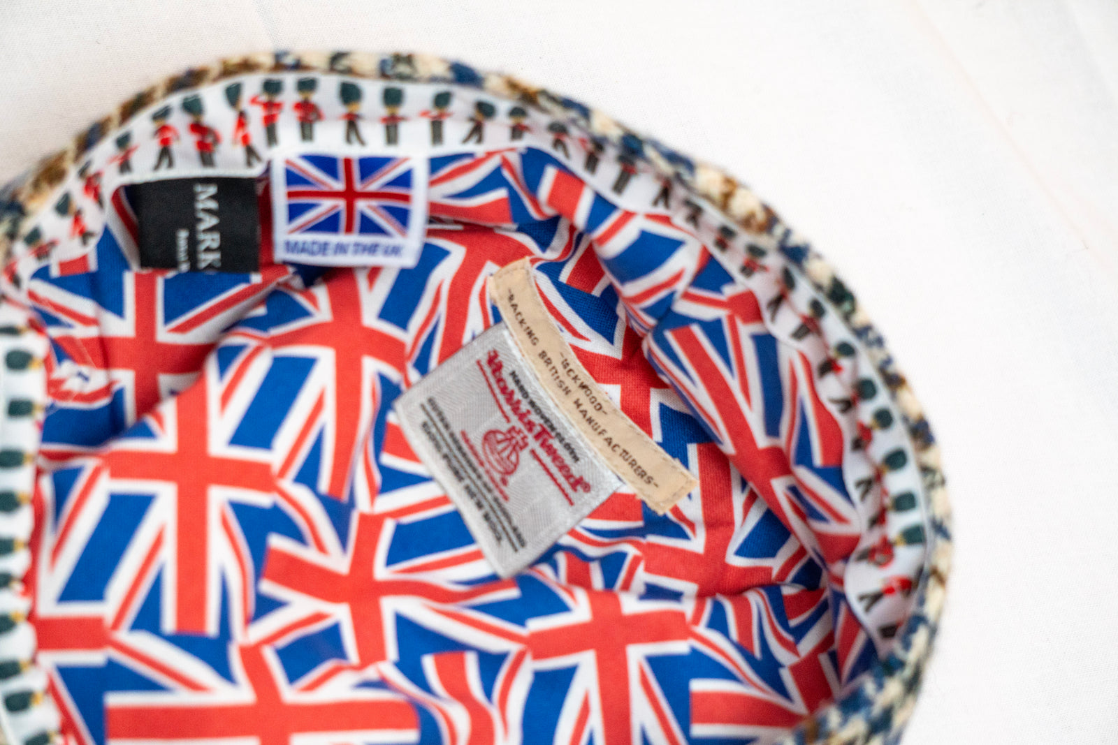 flat cap with Union Jack pattern and brand labels on a white background