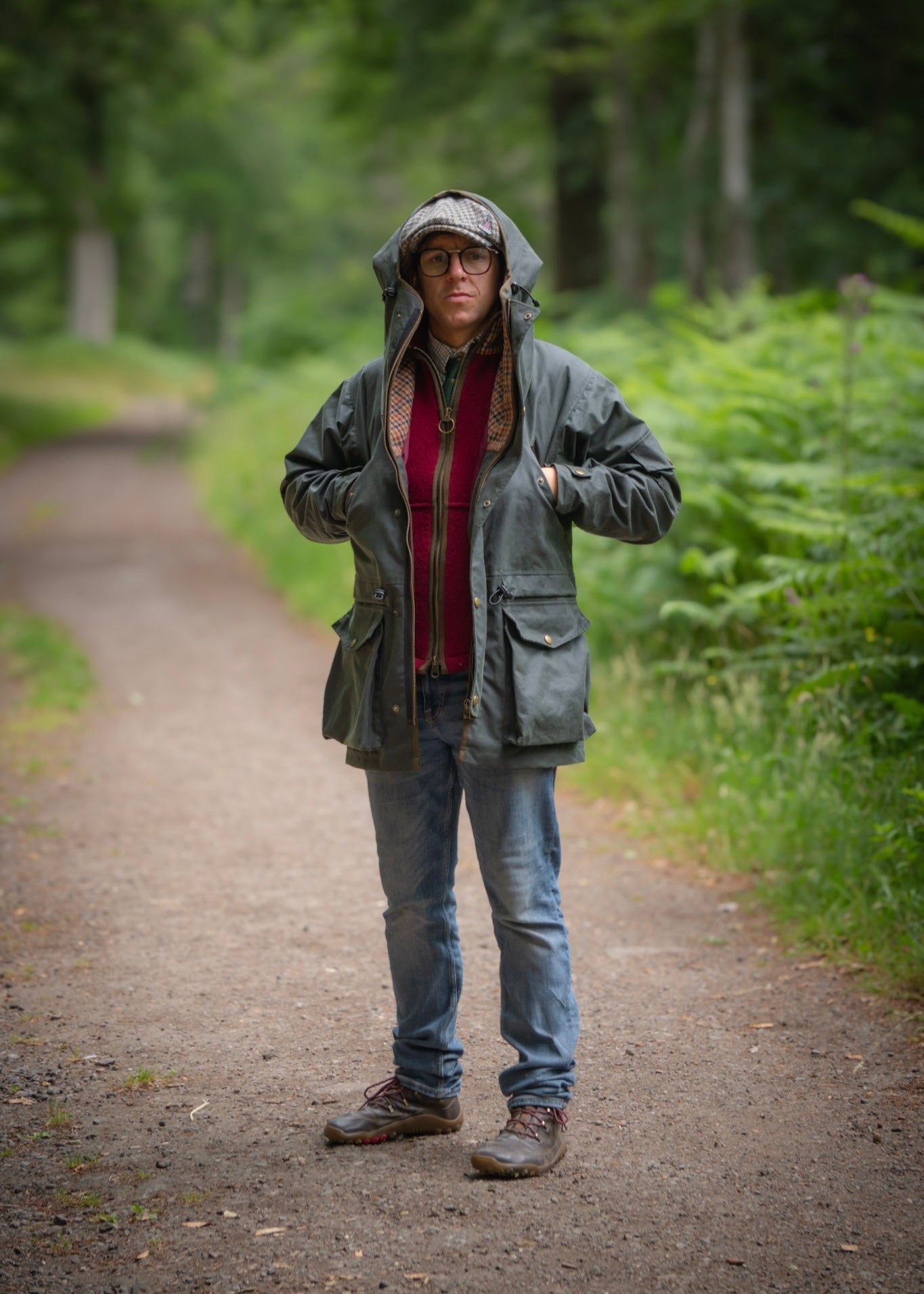 Person wearing a green raincoat on a forest path