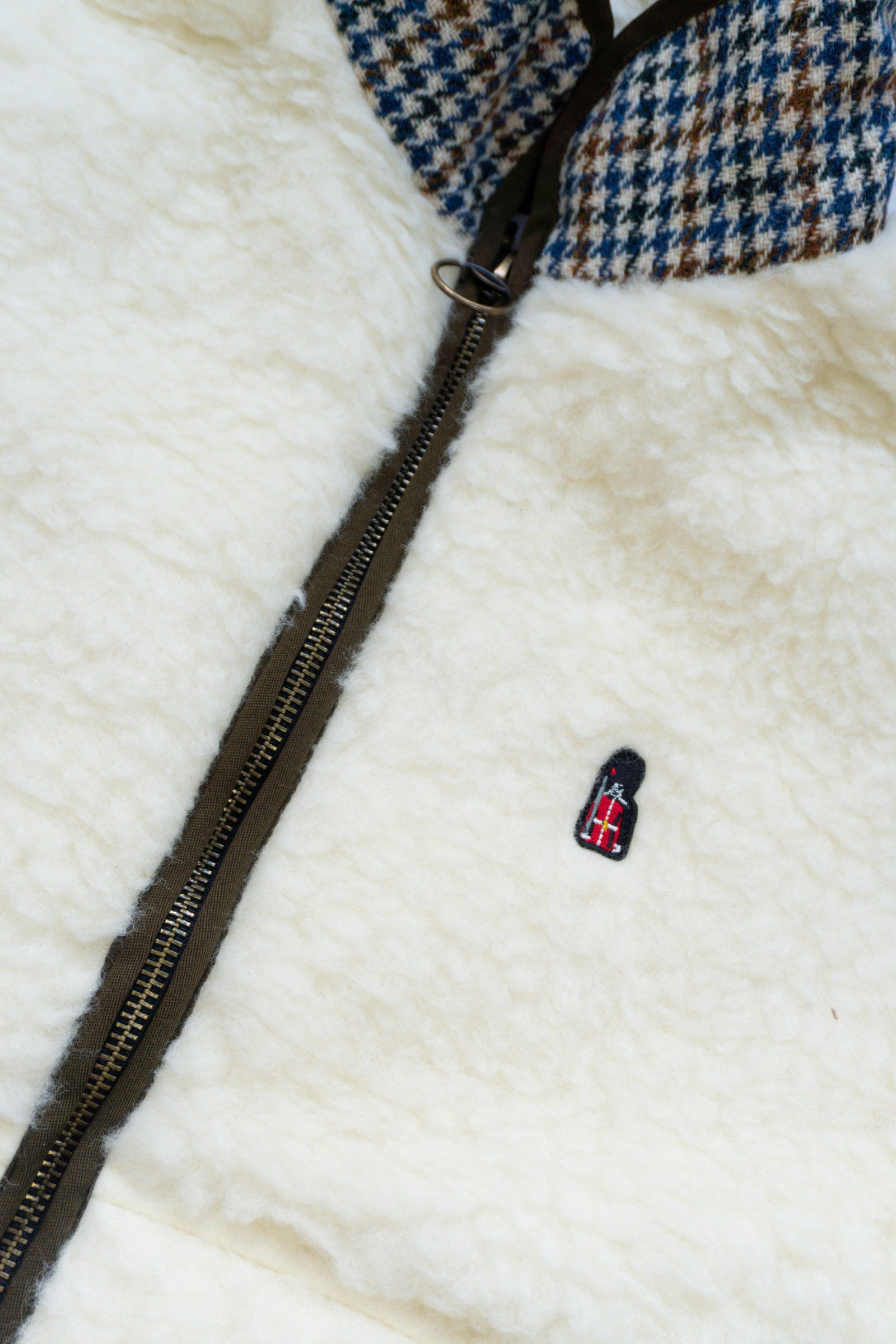 Close-up of a white fur jacket with a black zipper and a small logo on a white background