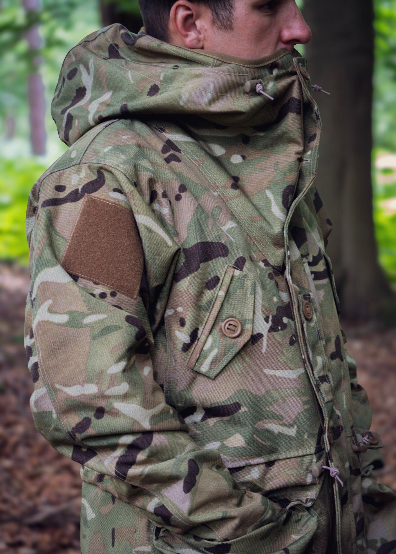 Person wearing a camouflage jacket in a forest setting