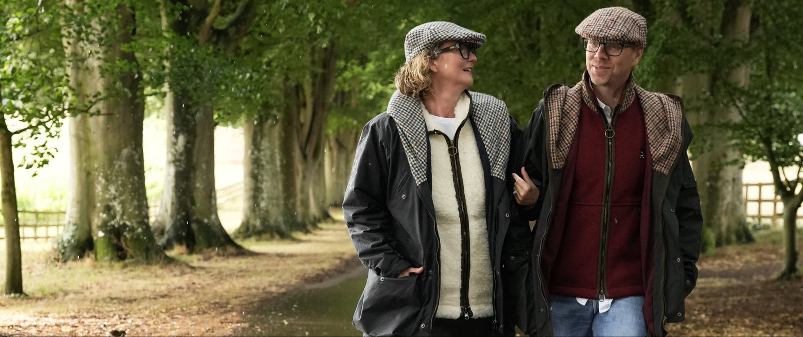 Two people walking together in a park with trees and a path.