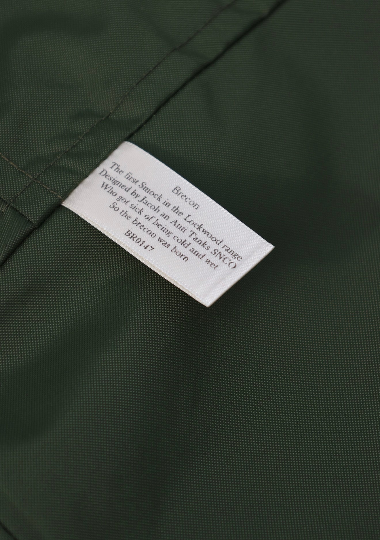 Close-up of a dark green textured fabric with a white sewn-in label reading Brecon.