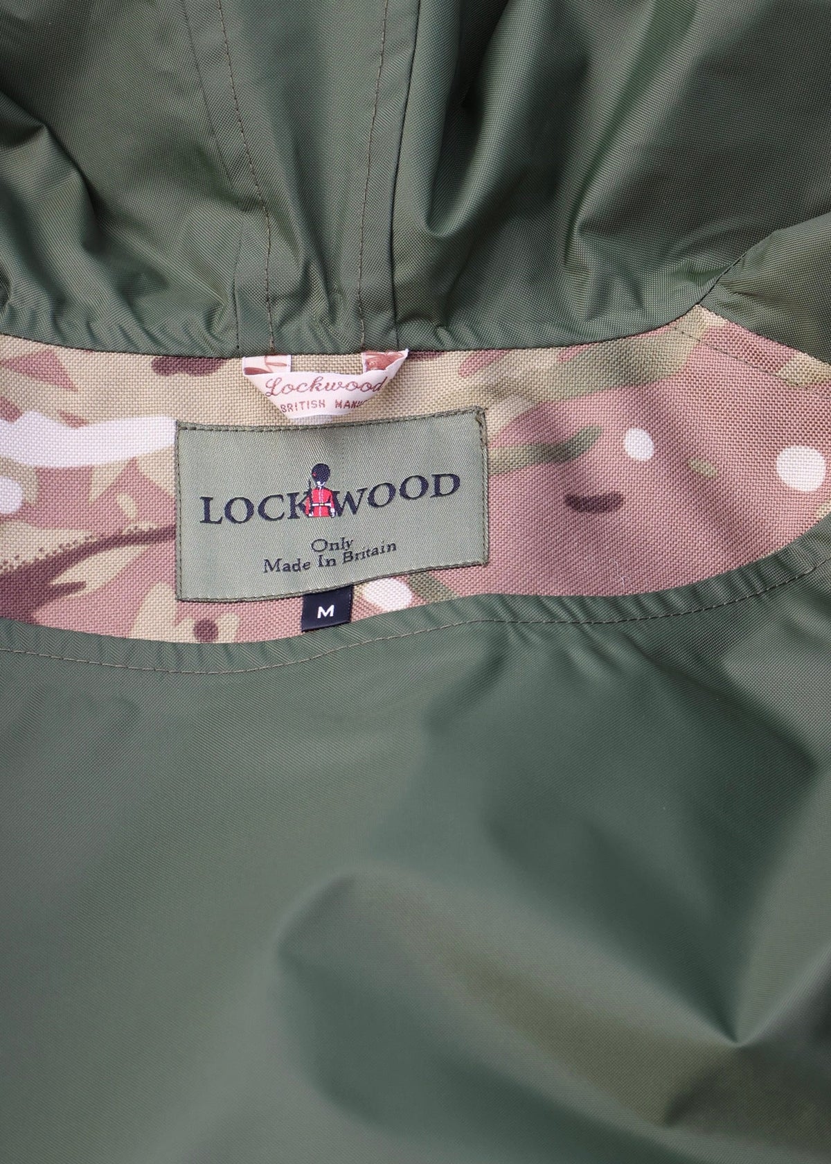 Close-up of a Lockwood jacket showing the olive green outer fabric, a camouflage inner lining, and the brand label.