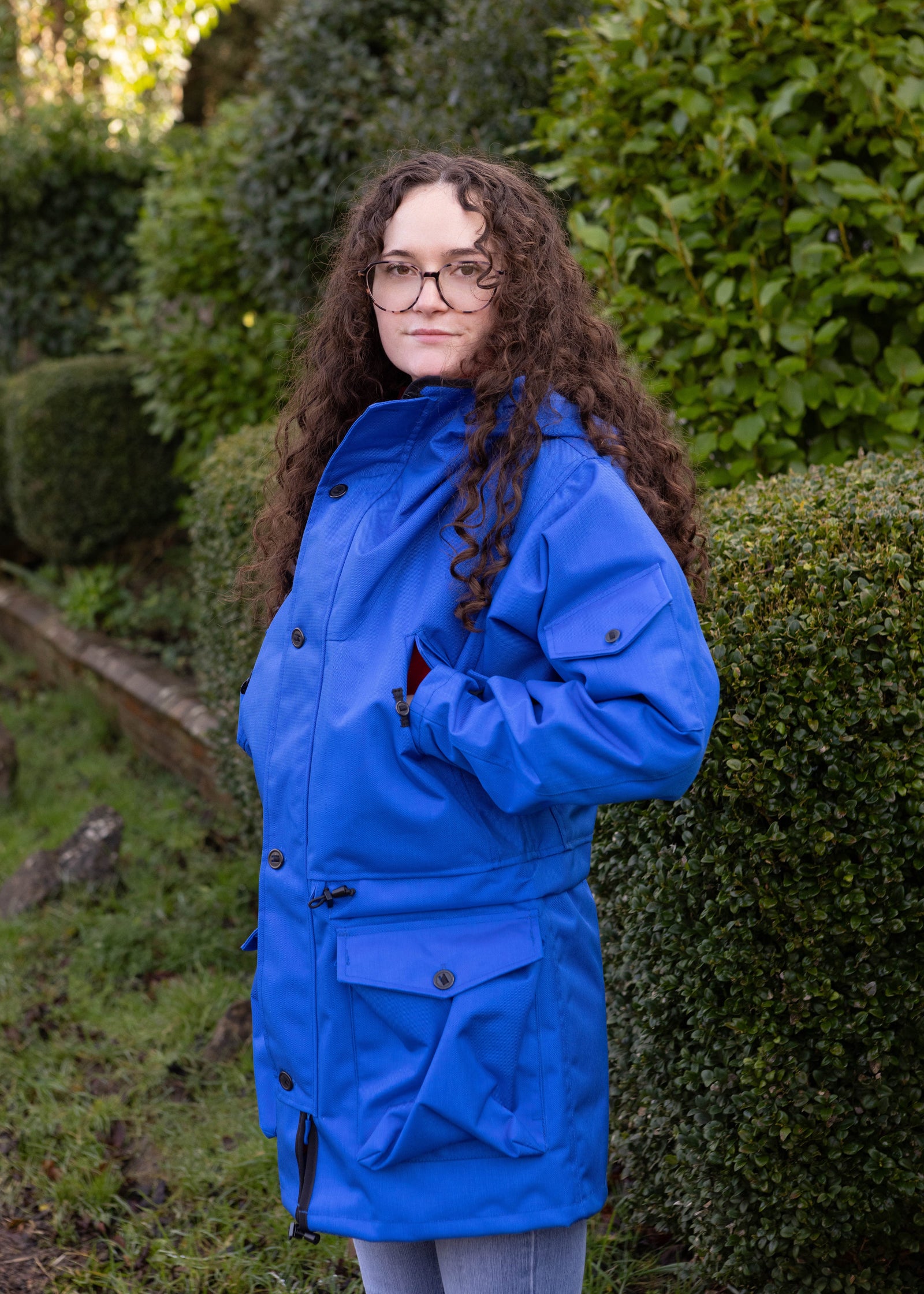 woman wearing waterproof jacket in royal blue while stood in a garden