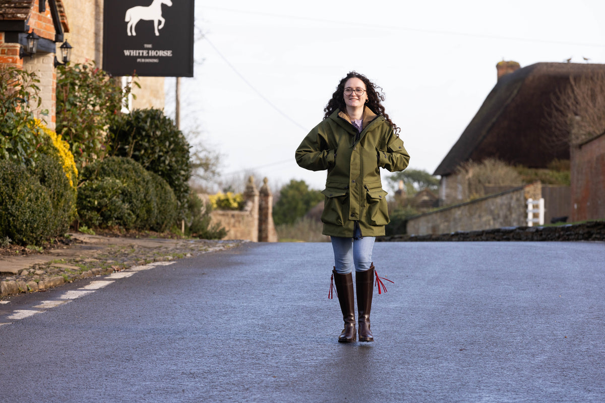 woman walking down a street wearing a green waterproof jacket