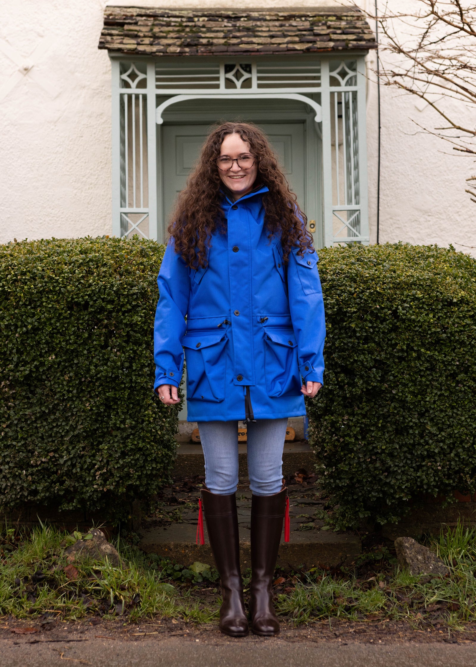 woman wearing a blue waterproof jacket soon in front of a cottage